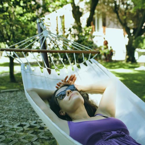 Une femme couché dans un hamac dans un jardin
