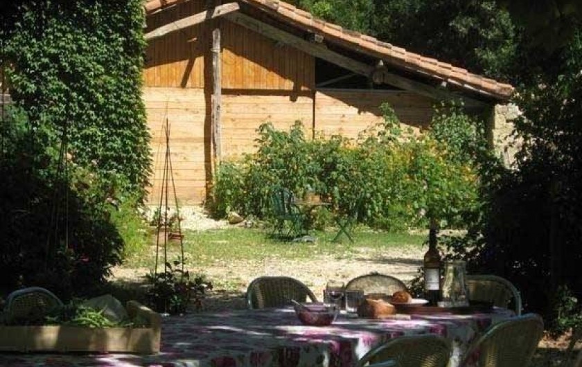 la table des repas sous les arbres, au fond la grange avec la cuisine d'été