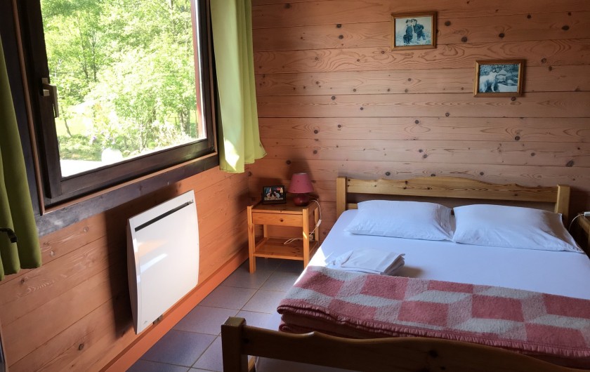 Location de vacances - Chalet à La Bresse - Chambre au RDC avec lit double, armoire et vue sur la terrasse.