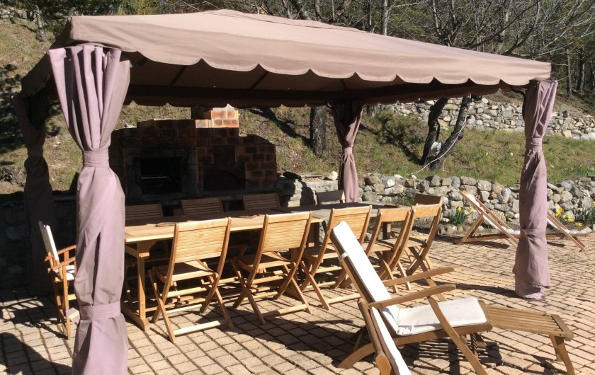 Location de vacances - Chalet à Barcelonnette - Le coin repas  accueille 16 personnes. Barbecue et four à pizzas, transats.