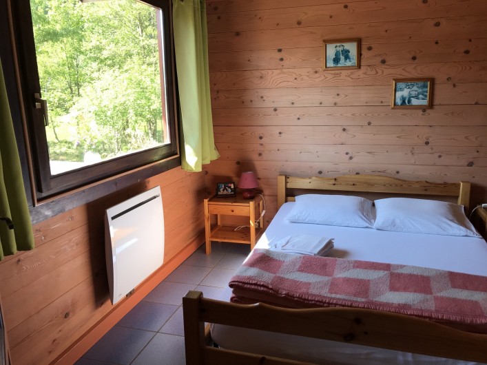 Location de vacances - Chalet à La Bresse - Chambre au RDC avec lit double, armoire et vue sur la terrasse.