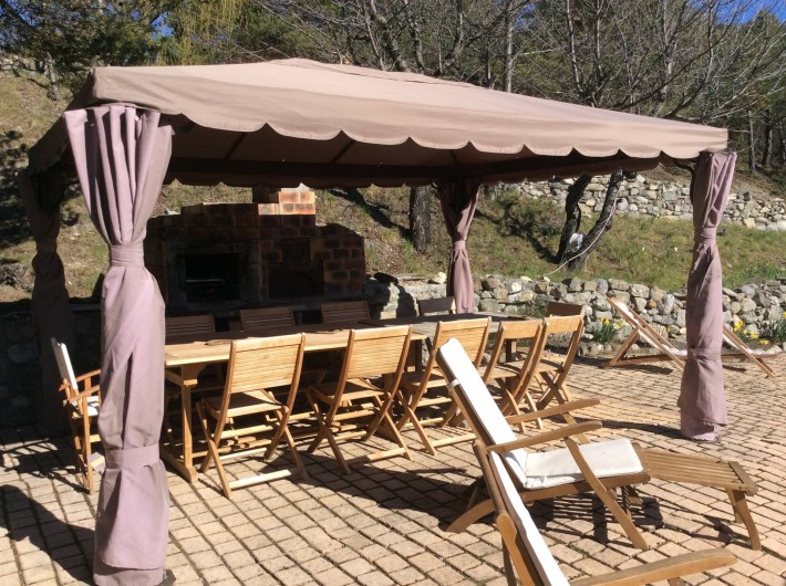 Location de vacances - Chalet à Barcelonnette - Le coin repas  accueille 16 personnes. Barbecue et four à pizzas, transats.