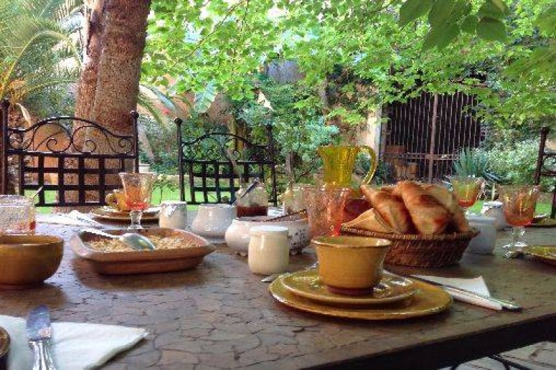 Location de vacances - Chambre d'hôtes à Fabrègues - Une vue gourmande du petit-déjeuner à l'ombre des palmiers.